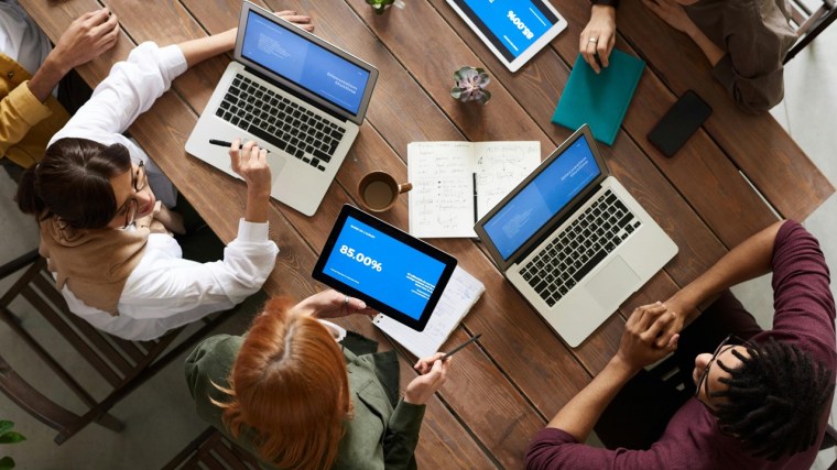 Personas trabajando en equipo con laptops, representación del aprendizaje compartido en entornos organizacionales.